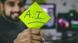Man holding a post-it note to the foreground with the letters A.I.