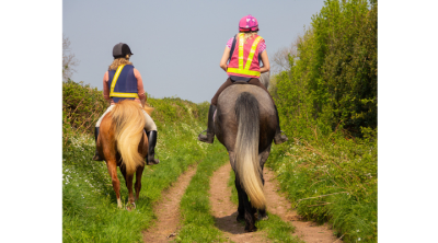 two horses with riders on a bridleway